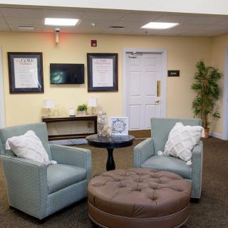 A cozy lobby seating area with chairs, an ottoman, and decorative elements.