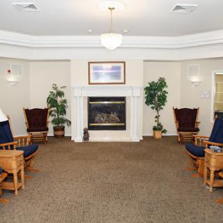 A cozy lounge area featuring comfortable seating and a fireplace, surrounded by indoor plants.