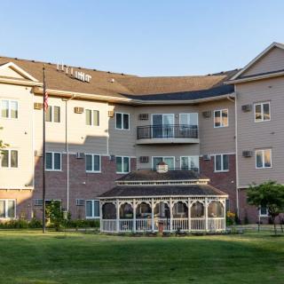 A residential apartment building with a gazebo and green lawn in the foreground.