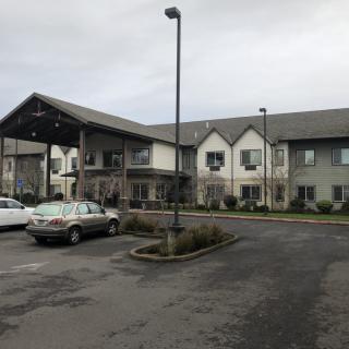 A two-story building with a parking lot and several cars on an overcast day.