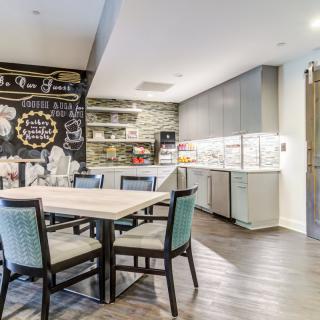 A modern kitchen and dining area with a chalkboard wall, ample seating, and sleek cabinetry.