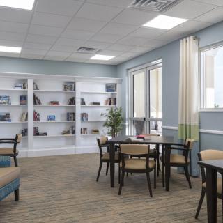 A modern library interior with bookshelves, tables, and chairs under bright lighting.