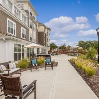 A well-maintained sidewalk with outdoor seating at a residential complex under a clear blue sky.