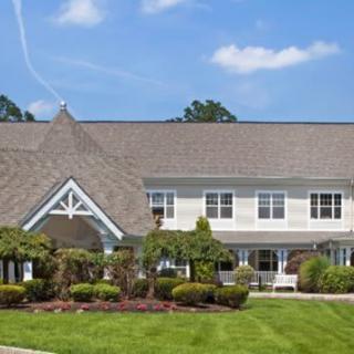 A large residential house with a well-maintained lawn and landscaped garden under a clear blue sky.