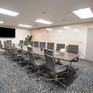 A modern conference room featuring a long table and ergonomic chairs, designed for professional meetings.
