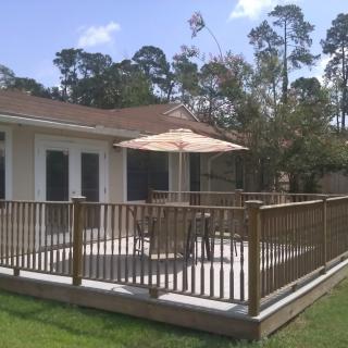 A backyard deck with outdoor furniture and an umbrella.