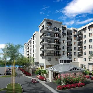 A modern apartment building with balconies and landscaped surroundings under a clear blue sky.