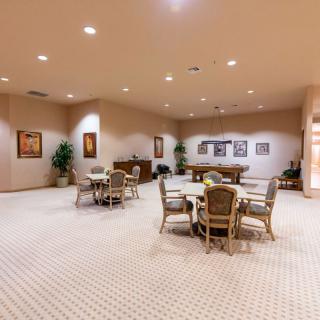 A spacious conference room with multiple round tables and chairs, decorated with plants and artwork.