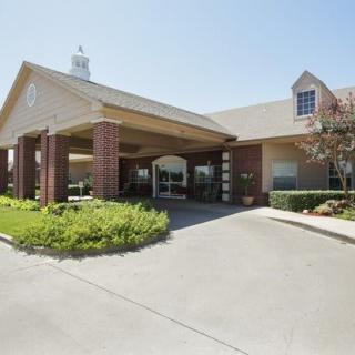 A building with a covered entrance and landscaped surroundings.