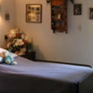 A cozy bedroom with a neatly made bed, floral arrangements, and wall decorations.