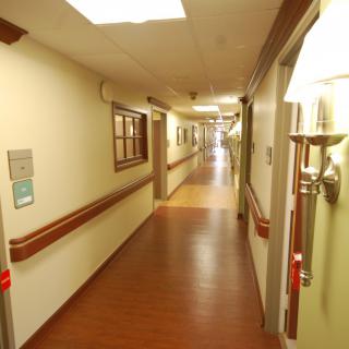 A long, well-lit hospital corridor with handrails along the walls.