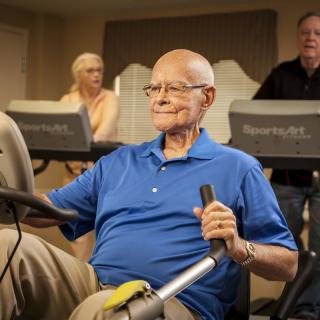 Elderly individuals exercising on gym equipment.