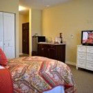 A cozy bedroom with a bed, dresser, and television, featuring warm colors and modern decor.