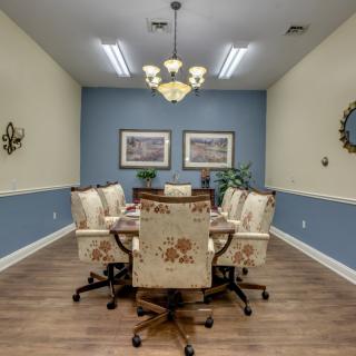 A well-decorated conference room with elegant chairs and a central table, featuring stylish lighting and wall art.