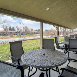 A covered patio with metal tables and chairs overlooking a grassy landscape on a sunny day.