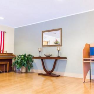 A cozy living room with a piano, console table, and a potted plant.