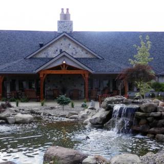 A picturesque building surrounded by a landscaped pond and waterfall.