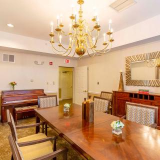 A well-appointed dining room featuring a large wooden table, elegant chandelier, and a piano in the corner.