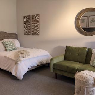 A cozy and stylish bedroom featuring a single bed, green couch, and tasteful decor.