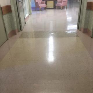 A clean hospital corridor with polished floors and soft lighting.