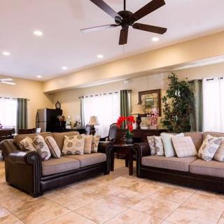 A spacious living room featuring two sofas, a ceiling fan, and tasteful decor.