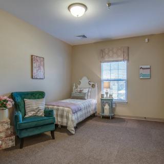 A cozy bedroom featuring a single bed and an armchair by the window.