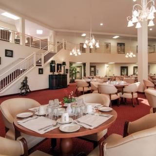 Elegant dining area with round tables, comfortable seating, and warm lighting.