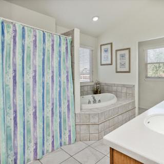 A serene and stylish bathroom featuring a shower with a colorful curtain and a spacious bathtub, accented by elegant tile work.