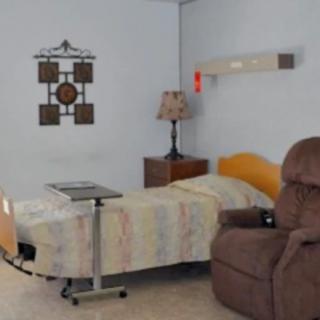 A hospital room with a bed, recliner, and lamp.