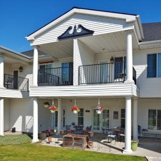 A modern two-story house featuring a spacious balcony and a well-maintained lawn under a clear blue sky.