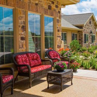 A cozy patio with wicker furniture and a beautifully landscaped garden in the background.