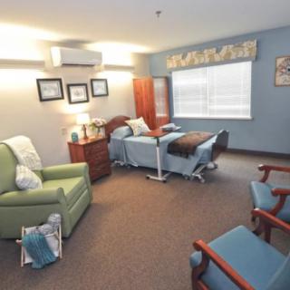 A comfortable hospital room with a bed, chairs, and a window letting in natural light.