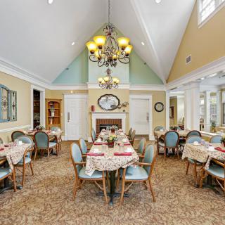 A spacious dining room with elegantly set tables and a grand chandelier.