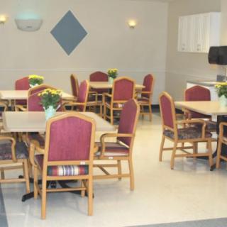 A neatly arranged indoor dining area with multiple tables and chairs, featuring decorative flowers on each table.