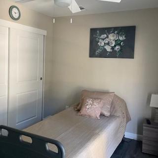A minimalist bedroom with a single bed, nightstand, and decorative painting.