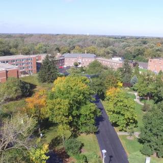 Aerial view of a campus surrounded by lush greenery and buildings.
