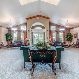 A spacious living room with elegant decor and furniture, featuring large windows and indoor plants.