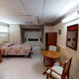 A cozy bedroom with a bed, table, and chairs near a window with curtains.