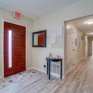 A minimalist hallway interior with a wooden door, mirror, and small table.