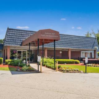 A welcoming entrance of a facility surrounded by well-maintained gardens under a clear blue sky.