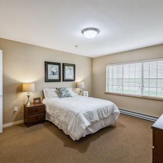 A cozy bedroom with a neatly made bed, bedside tables, and soft lighting.