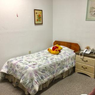 A cozy single bedroom with a floral bedspread and nightstand.