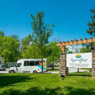 A shuttle bus parked near a sign at a park on a sunny day.