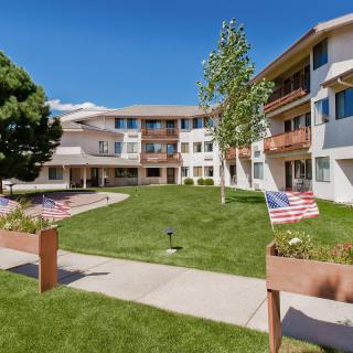 A sunny day in a courtyard of an apartment building with well-maintained grass and small American flags along the walkway.