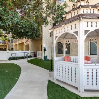 A charming white gazebo sits beside a winding pathway, surrounded by lush greenery.