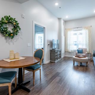 A modern living and dining area with wood flooring, featuring stylish furniture and ample natural light.