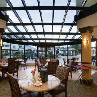 A spacious restaurant interior with elegantly set tables and a glass ceiling.