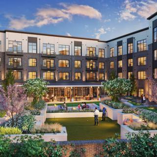 A modern apartment building with a landscaped courtyard in the evening.