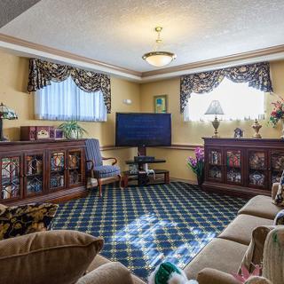 A cozy living room with a television, sofa, and bookshelves adorned with decorative curtains and lamps.
