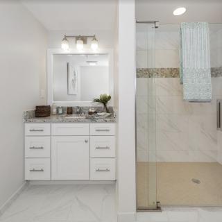 A modern bathroom with a white vanity and a spacious glass-enclosed shower.